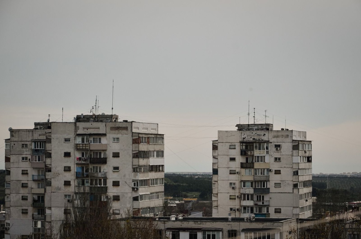 Two grey apartment blocks seen across rooftops under an overcast sky