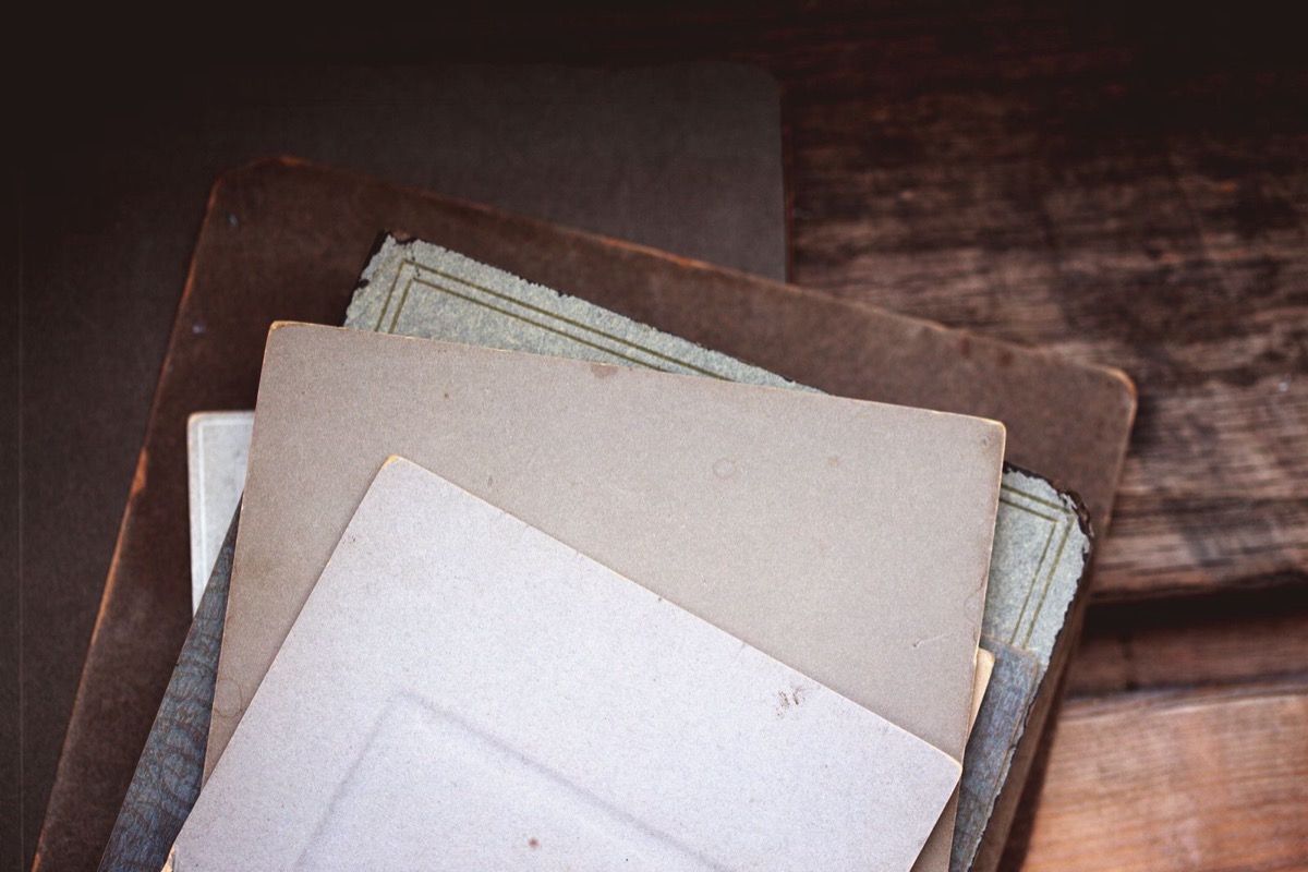 A stack of grey and brown cardboard folders on a dark wooden desk