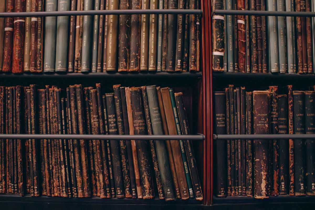 Shelves of old bound volumes with worn leather spines in a bookcase
