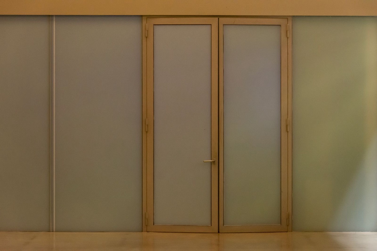 Closed frosted-glass doors in a wooden frame on a plain wall of an empty room