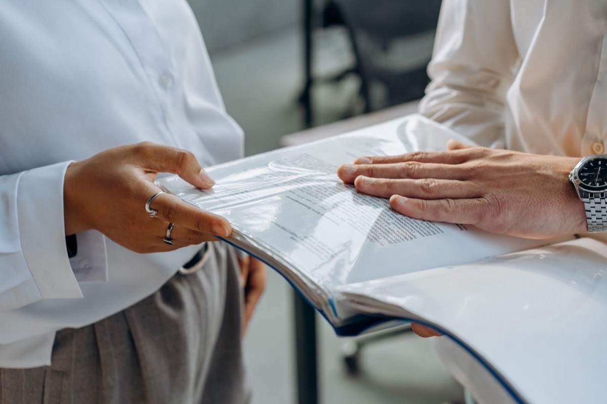Two people's hands on a clear plastic document folder