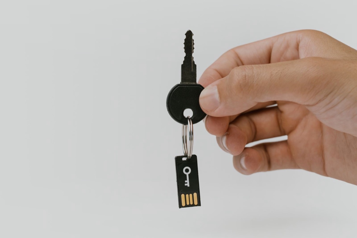 A hand holding a key with a small USB drive attached